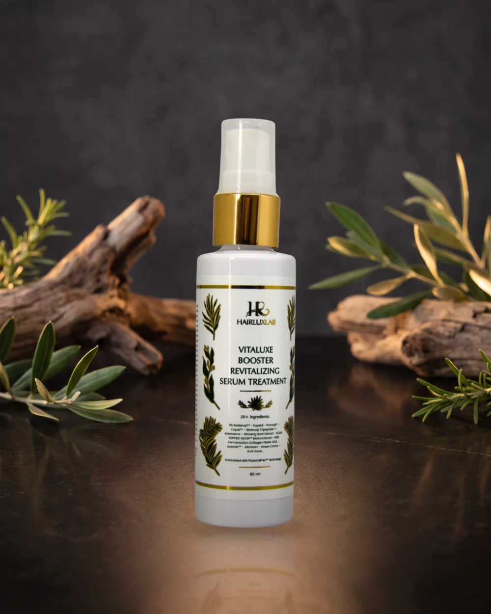 Botol HairLuxLab Vitaluxe Booster Revitalizing Serum Treatment 60 ml di atas batu gelap, dengan kayu apung dan daun zaitun di belakangnya